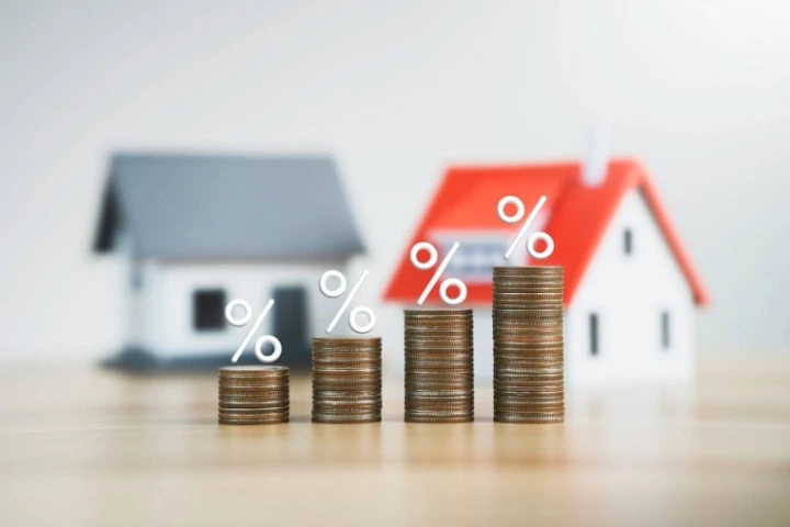 Évolution des taux d'intérêt et du financement immobilier au Luxembourg, illustrée par des pièces, des pourcentages et des maisons.
